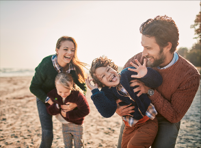 Two parents play with their children on the beach