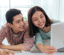 asian couple happy reviewing their finances on a computer tablet