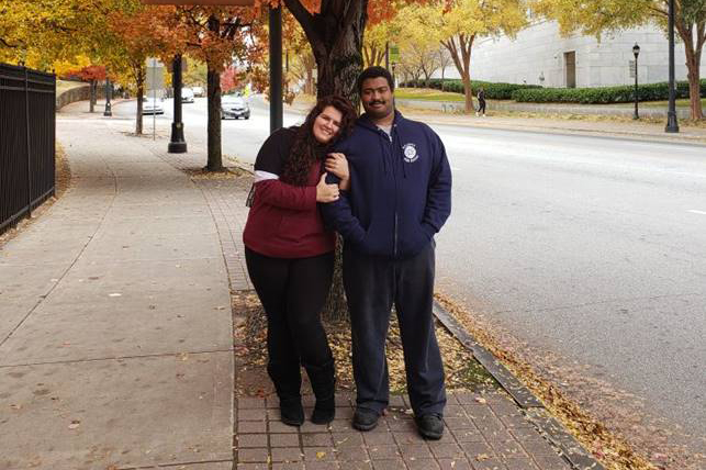 A couple posing under a tree in the fall.